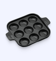 Black muffin tin with multiple compartments on a white background