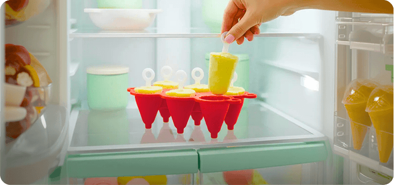 Colorful ice cream mold in a refrigerator with a hand holding a popsicle.