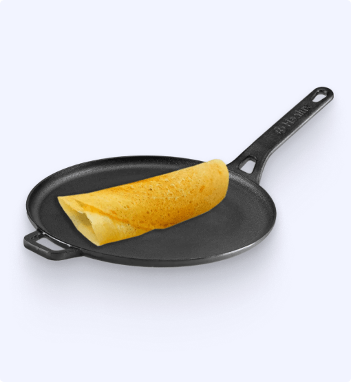 Rolled crepe on a black frying pan against a white background