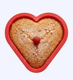 Heart-shaped cake with a raspberry in the center on a white background