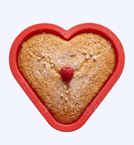 Heart-shaped cake with a raspberry in the center on a white background