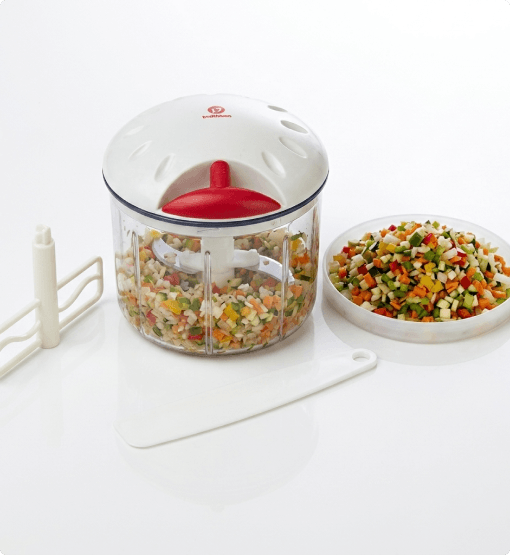 Vegetable chopper with chopped vegetables on a white surface