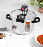 Stainless steel pressure cooker on a speckled countertop with spices and a bowl of food.