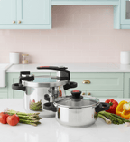 Stainless steel cookware set on a kitchen counter with vegetables