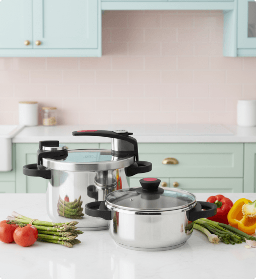 Stainless steel cookware set on a kitchen counter with vegetables