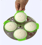 Green rice cooker with four compartments filled with white rice on a white background