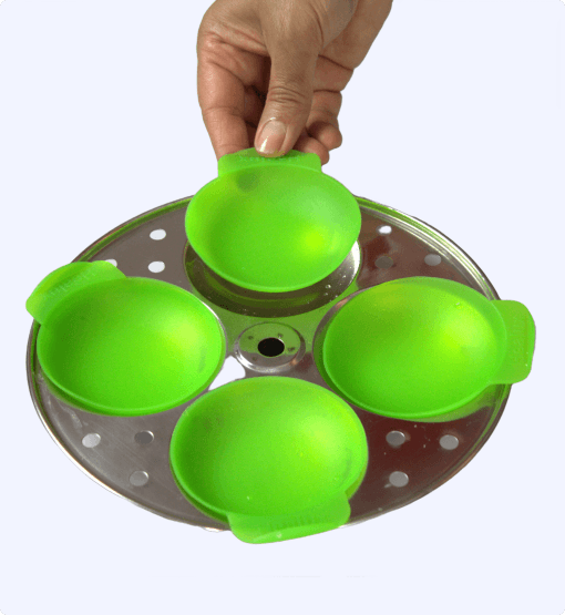 Green egg poacher on a metal tray with a hand lifting one of the compartments.
