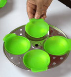 Green silicone egg poacher on a metal tray with a hand lifting one of the poachers.