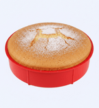 Round cake with powdered sugar in a red cake pan on a light gray background