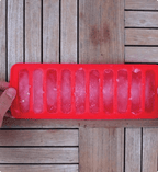 Red silicone ice cube tray on a wooden surface