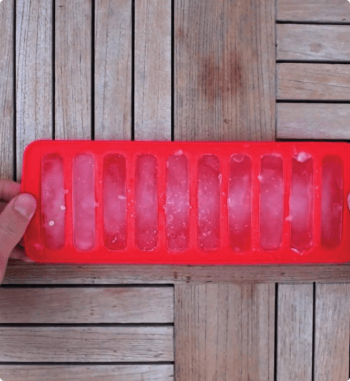 Red silicone ice cube tray on a wooden surface