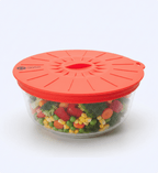 Glass container with colorful vegetables and an orange lid on a white background
