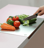 Person cutting vegetables on a glass cutting board with a knife