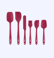 Set of red silicone kitchen utensils on a white background
