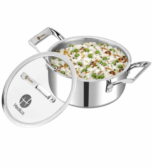 Stainless steel pot with lid containing a dish of rice and peas on a white background