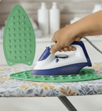 Person using a blue and white iron on an ironing board with a green ironing board cover.