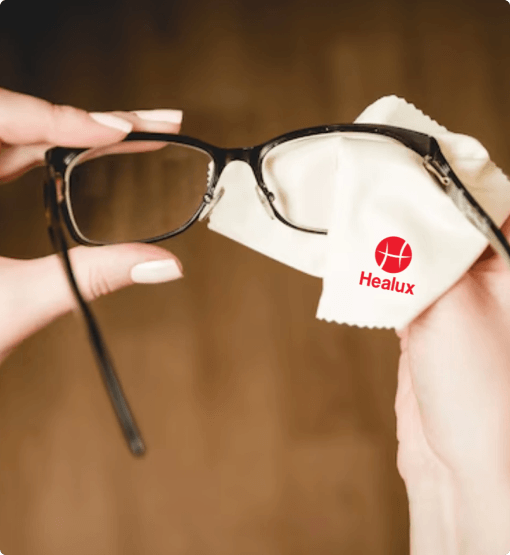 Person cleaning glasses with a Healux cloth on a blurred background