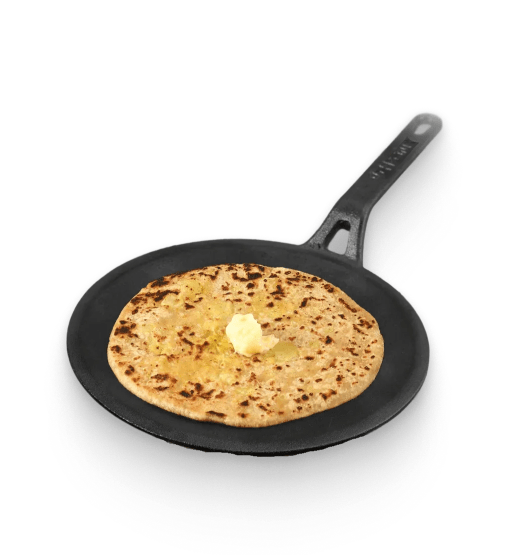 Flatbread with butter on a black frying pan against a white background