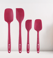 Set of four red silicone spatulas on a white background